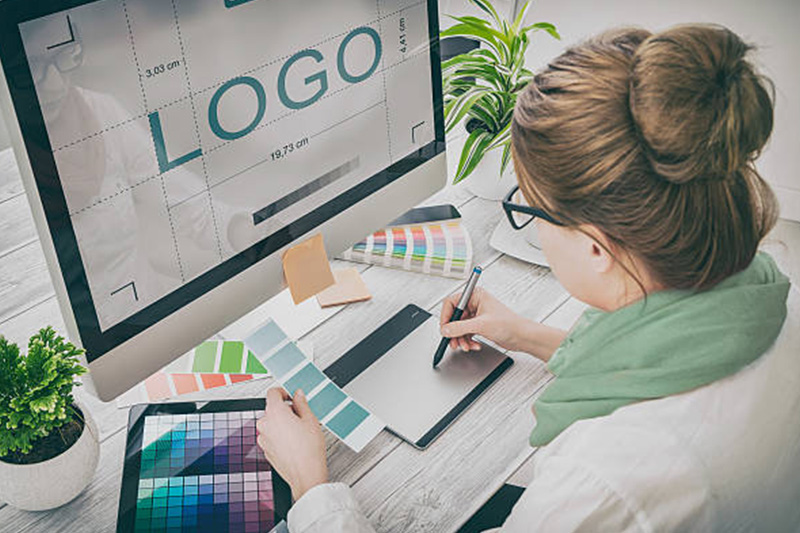 Lady sitting in front of computer designing a logo